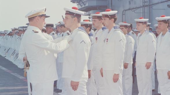 Au moment où il quitte le commandement du Clemenceau, le capitaine de vaisseau Lefebvre décore les appelés du contingent de la médaille de la Défense nationale. A la fin des années 1980, tant sur le Foch que sur le Clemenceau, de nombreux marins de l’équipage sont des appelés du contingent. Par exemple, les conducteurs et le personnel de pont d’envol (CONEV et PONEV) le sont tous à l’époque. ©Philippe LECOMTE/ECPAD/Défense