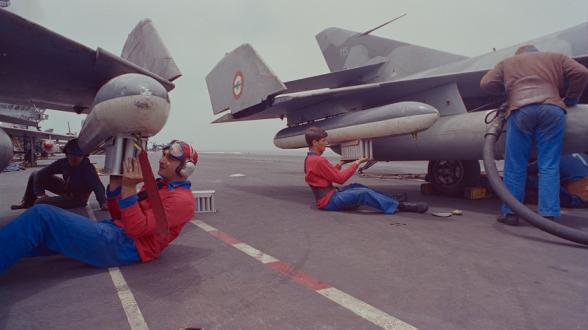 Les spécialistes de la maintenance de l’armement aéronautique installent les leurres sur les Super Etendard. Les « Boum » sont reconnaissables sur le pont d’envol à leur maillot rouge orné d’une barre noire verticale. ©P. LECOMTE/ECPAD/Défense