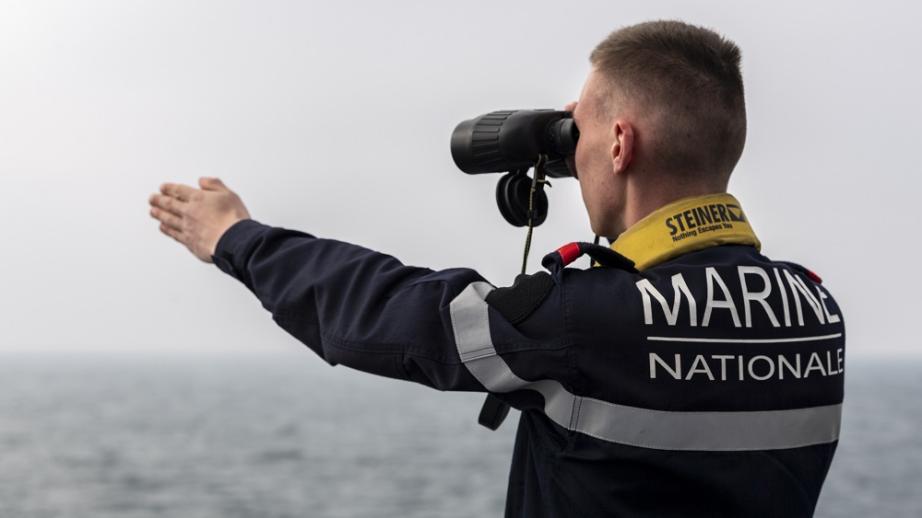 Un marin regarde aux jumelles à bord de la frégate Guépratte