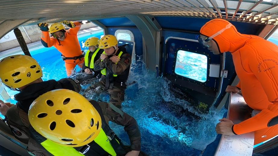 Un groupe de marins pompiers s'entraine dans une cabine immergée