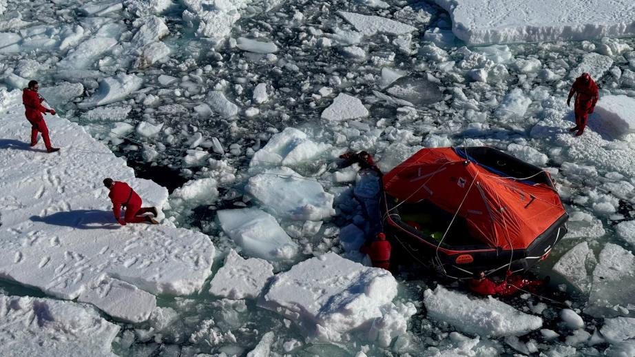 Un groupe de marins tire un radeau de sauvetage à travers la banquise