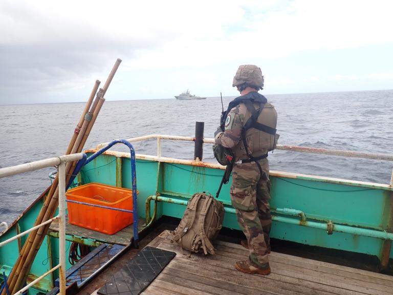 Un membre de l'équipe de visite en arme regarde vers le Bougainville en arrière plan