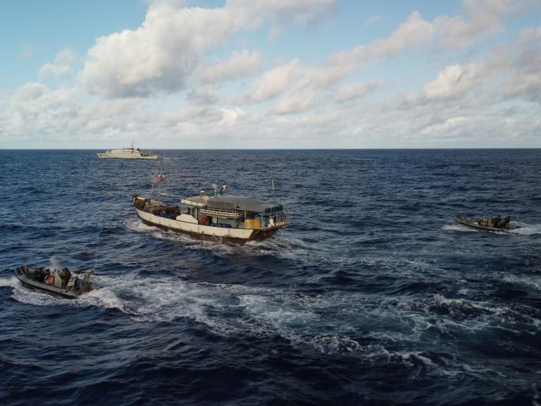 Un bateau, encerclé par deux zodiac et une frégate