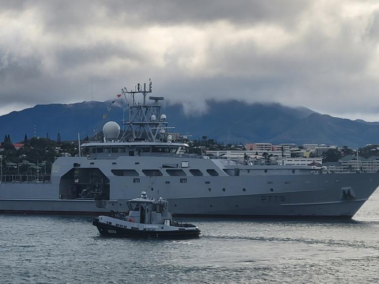 un navire de la Marine à quai, avec l'île de Nouméa en fonbd
