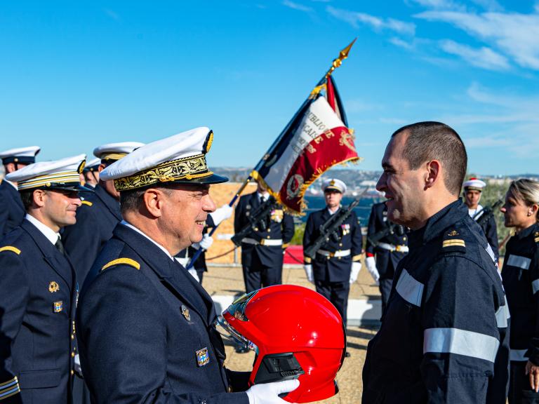 Une autorité remet un casque rouge à un officier des marins-pompiers de Marseille